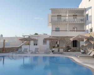 a pool with chairs and umbrellas next to a building at Mykonos Essence Adults Only in Ornos