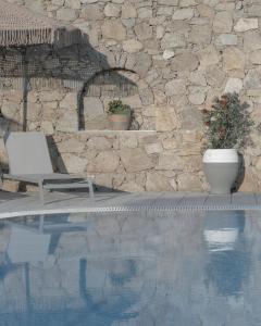 una piscina con sedia accanto a un muro di pietra di Mykonos Essence Adults Only a Ornos
