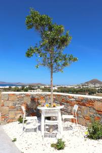 un tavolo con sedie e un albero di fronte a un muro di pietra di The Nine Graces - Agia Anna - Option With private pool or hot tub ad Agia Anna Naxos