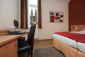 ein Hotelzimmer mit einem Bett und einem Schreibtisch mit einem Stuhl in der Unterkunft Hotel Alt Speyer in Speyer