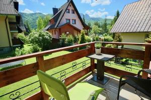 a balcony with a table and chairs and a house at Apartament BazaTatry Wielka Krokiew in Zakopane