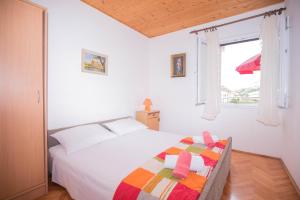 ein weißes Schlafzimmer mit einem Bett und einem Fenster in der Unterkunft Apartments Salis in Pag