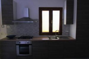 une cuisine avec évier et cuisinière ainsi qu'une fenêtre dans l'établissement Apartment - La dolce vita - where dreams come true, à Valledoria