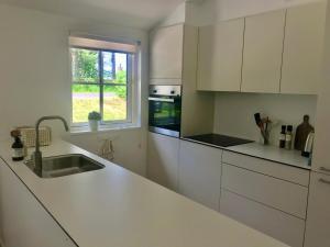a white kitchen with a sink and a window at Sommerhus Mossø in Skanderborg