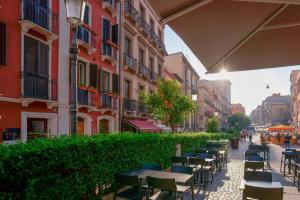 una fila de mesas y sillas en una calle con edificios en Le Suite Sul Corso, en Cagliari