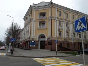 a large yellow building on a street with a crosswalk at Отель НОХЧОСТАР in Groznyy