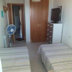 a bedroom with two beds and a tv and a dresser at A 300 mètre de la plage plein centre alcossebre in Alcossebre