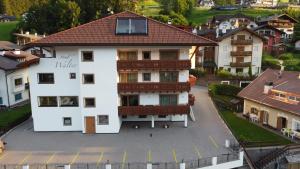 un grand bâtiment blanc avec un toit rouge dans l'établissement Hotel Garni Walter, à Ortisei