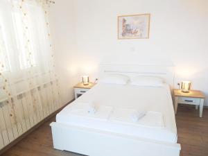 a white bed in a room with two tables at Apartments Antonio in Senj