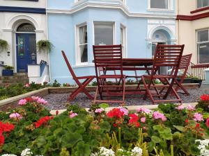 dwa krzesła i stół w ogrodzie z kwiatami w obiekcie Frosty Towers w mieście Llandudno