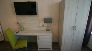 a desk with a green chair and a monitor on a wall at Hotel Bee Fang in Hamburg