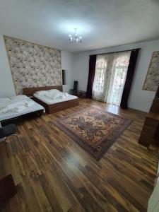 a living room with two beds and a wooden floor at Pensiunea Eden in Băile Olăneşti