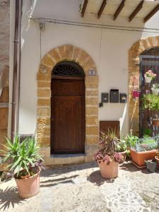 une porte en bois dans un bâtiment avec des plantes en pot dans l'établissement Balcone delle mura, à Cefalù