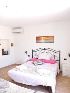 - une chambre blanche avec un grand lit et des oreillers roses dans l'établissement Balcone delle mura, à Cefalù