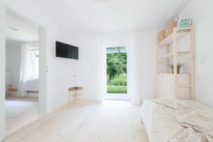 a white bedroom with a bed and a tv at Nordic Bo - Wellen, Wald und wilde Küste in Surendorf