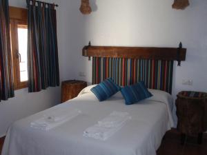 a bedroom with a white bed with blue pillows at El Molino de Iramala in Reolid