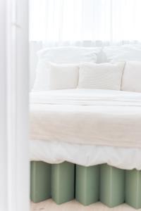 a white bed with white sheets and pillows at Nordic Bo - Wellen, Wald und wilde Küste in Surendorf