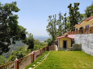 a house with a balcony and a yard at Kyarki Resort in Rishīkesh