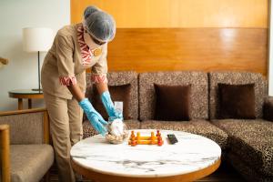 a woman is cleaning a table in a living room at Welcomhotel by ITC Hotels, Devee Grand Bay, Visakhapatnam in Visakhapatnam