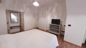 Un dormitorio con una cama blanca y un televisor. en La Chicca in centro - Centro storico Ascoli Piceno, en Ascoli Piceno