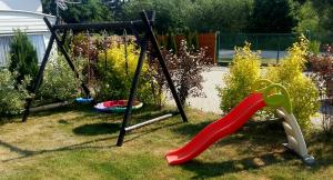 um parque infantil com escorrega e um baloiço em Domki holenderskie ,, Latający Holender" em Dębki