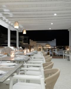 un comedor con mesas blancas y sillas blancas en Mykonos Essence Adults Only, en Ornos