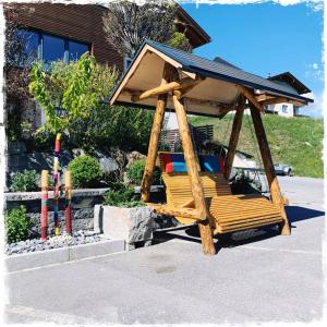 a wooden swing with a roof on top of it at Hotel Garni Alpendiamant in Fiss