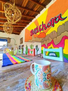 una taza de café sobre una mesa en una habitación con un mural en Hostel Trip Monkey Barichara en Barichara