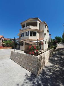 a house on a stone wall with flowers on it at Apartments Kim in Rab