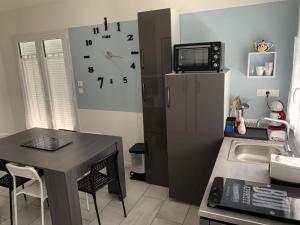 Il comprend une cuisine équipée d'une table, d'un réfrigérateur et d'une horloge. dans l'établissement Idéale famille, tout y est !, à Dompierre-sur-Besbre