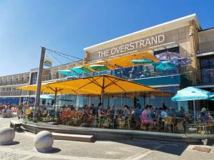 a group of people sitting at a restaurant under umbrellas at Poseidon Friends in Bournemouth
