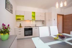 uma cozinha com armários brancos e uma mesa com flores em Apartmani Marica em Plomin
