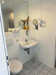 a bathroom with a toilet and a sink and a mirror at Hotel am Park in Willich