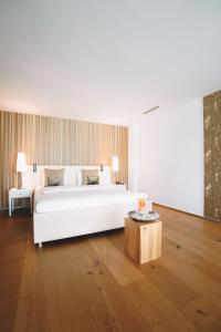 a bedroom with a large white bed and a table at Hotel AVA in Sempach Station