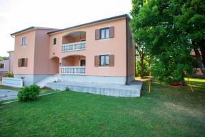 a large pink house with stairs and a yard at Apartmani Marica in Plomin