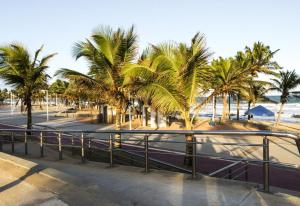 a beach with palm trees and a road with a fence at Apartamentos Itapuã Residence - Praia in Salvador