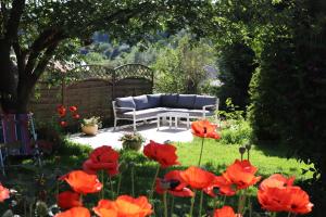 a garden with a couch and red flowers at L'Herbe Haute in Honfleur