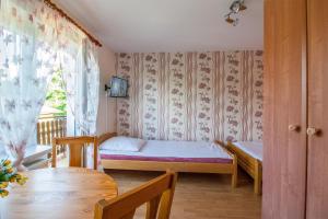 Zimmer mit 2 Betten, einem Tisch und einem Fenster in der Unterkunft Bieszczadzkie Wzgórze in Myczków