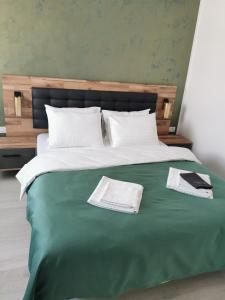 een bed met een groene deken en twee boeken erop bij Apartment no 11 - Amarilia Apartments in Constanţa