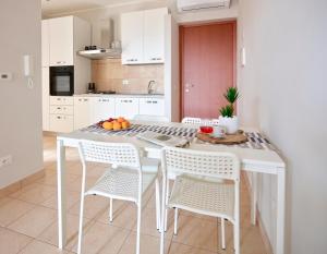 cocina blanca con mesa y sillas en Sibylla Apartment, en Sperlonga