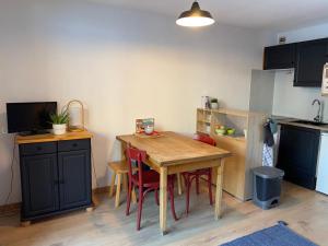 uma pequena cozinha com uma mesa de madeira e cadeiras em Location studio plein centre Les Carroz em Les Carroz d'Arâches