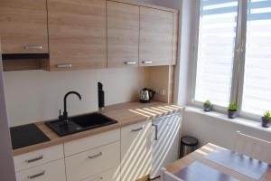 cocina con armarios de madera, fregadero y mesa en Apartament Assolato en Władysławowo