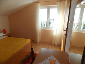 a bedroom with a bed and a table and windows at Apartments and Rooms Jasna in Hvar