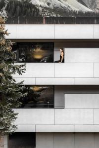 a woman looking out of a window of a building at Ciasa de Munt Lifestyle Living in Corvara in Badia