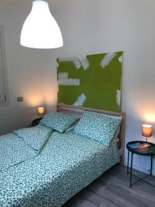 a bedroom with a bed with a green headboard and two lamps at APPARTAMENTO TURISTICO - VIA MONTENUDO in Casalzuigno