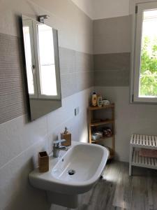 bagno con lavandino bianco e specchio di APPARTAMENTO TURISTICO - VIA MONTENUDO a Casalzuigno
