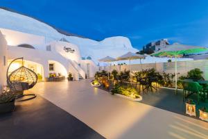 a patio with tables and chairs and umbrellas at night at Santoterra Antigua Suites in Karterados