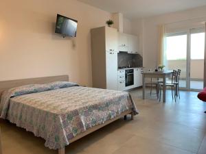 a bedroom with a bed and a kitchen with a table at Residence Capinera in Sottomarina