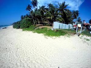 uma praia branca com palmeiras e uma casa em Ramon beach resort em Ambalangoda