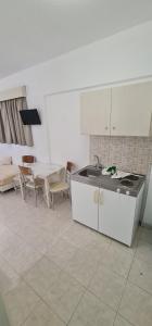 a kitchen with a sink and a table and chairs at Elarin studios & apartments in Faliraki